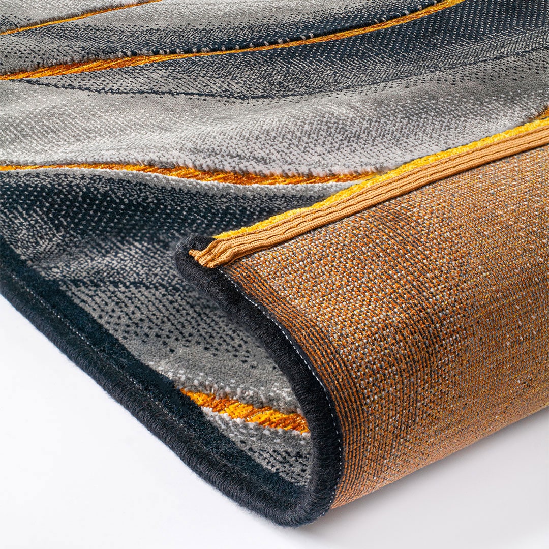 Gros plan sur le motif 3D à ondes et les courbes jaune-orange du tapis Gabrielle Ondes Gris Jaune