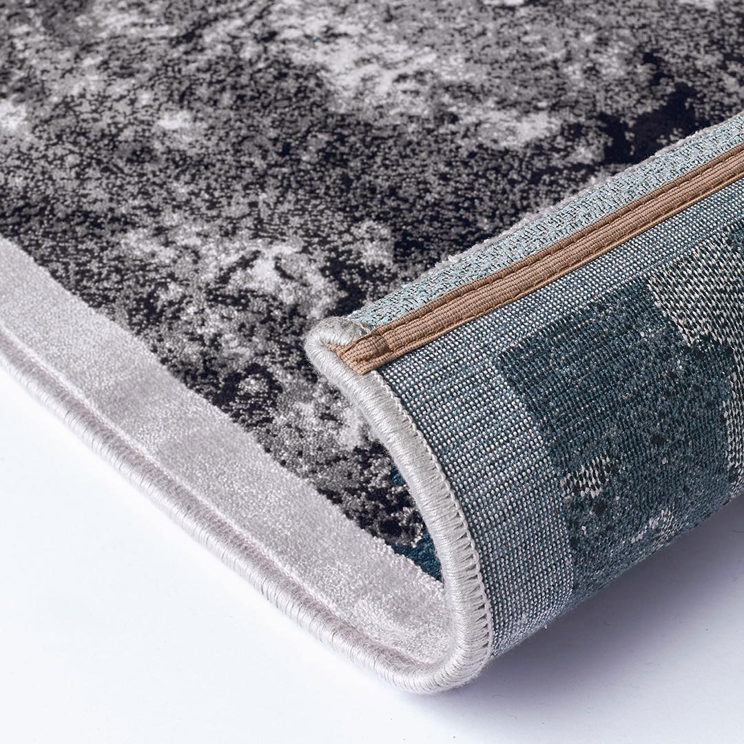 Gros plan sur les reflets turquoise du tapis Gabrielle